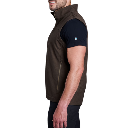 A man shown in side profile wearing a dark brown sleeveless zip-front vest over a black short-sleeve shirt, against a plain white background.