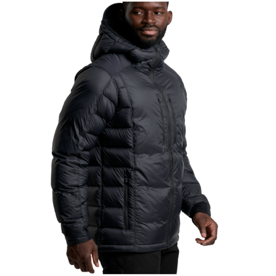 A man wearing a black hooded puffer jacket, shown from the chest down against a plain white background.