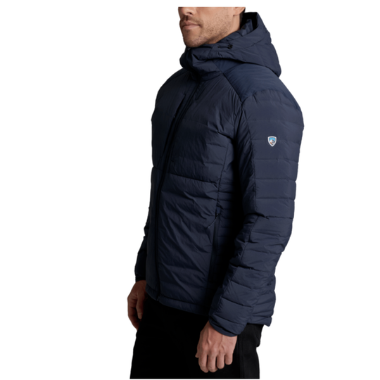 A man wearing a navy blue hooded puffer jacket, shown in a side profile view against a plain white background.