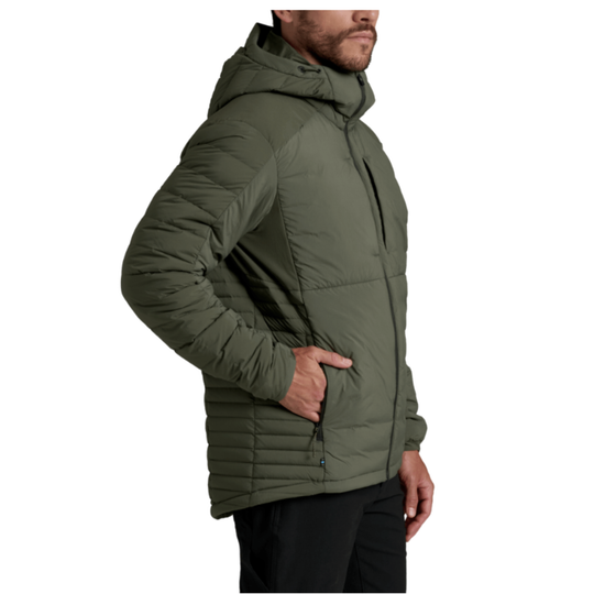 A man wearing an olive green hooded puffer jacket, shown in a side profile against a plain white background.