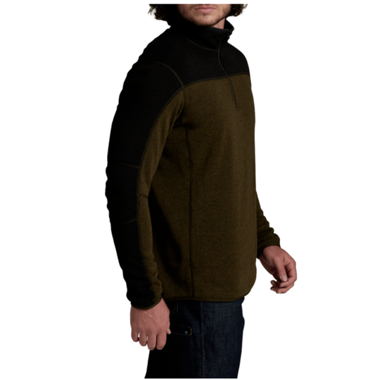 A man wearing a color-blocked quarter-zip fleece pullover sweater with a black yoke and shoulders, and an olive green body and sleeves, shown from a side profile against a white background.