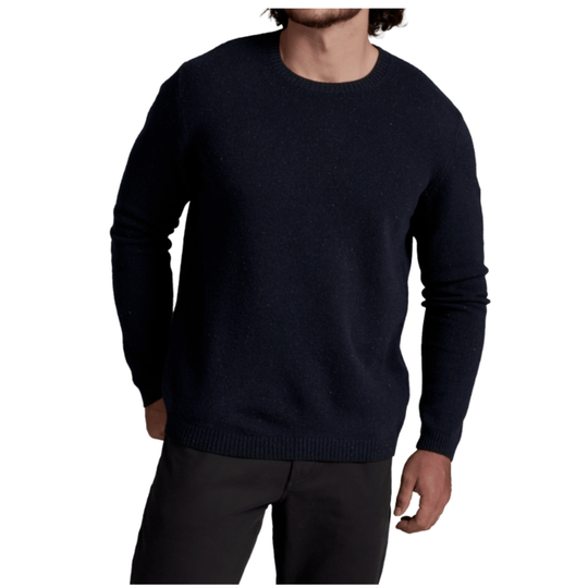 A man wearing a dark navy blue crewneck knit sweater and dark trousers, shown from the chin down against a plain white background.
