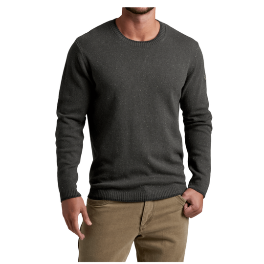 A man wearing a dark charcoal gray crewneck sweater and tan pants, shown from the chin down against a plain white background.
