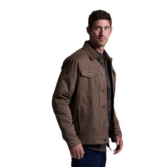 A man wearing a brown button-up trucker jacket over a dark shirt and blue jeans, photographed against a plain white background.