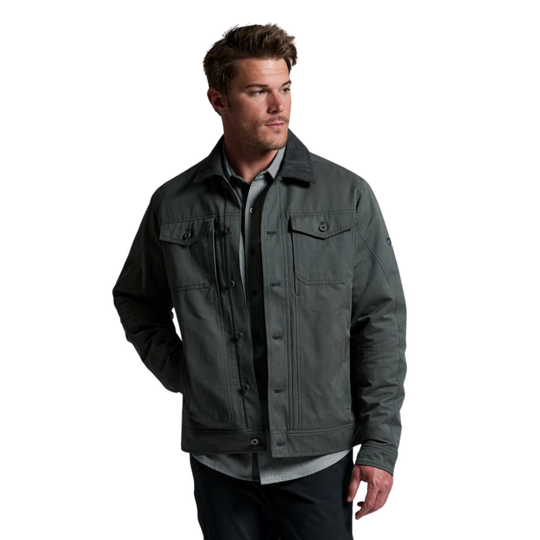 A man wearing a dark gray utility jacket over a gray button-up shirt and dark pants, photographed against a plain white background.