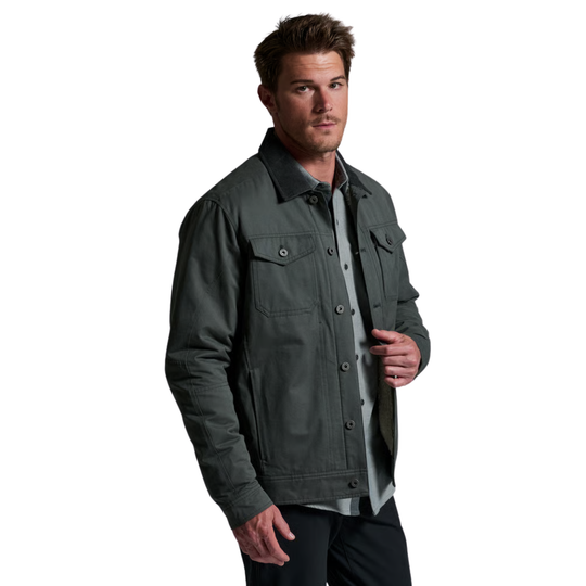 A man wearing a dark gray utility jacket over a light gray button-down shirt, photographed against a solid white background.