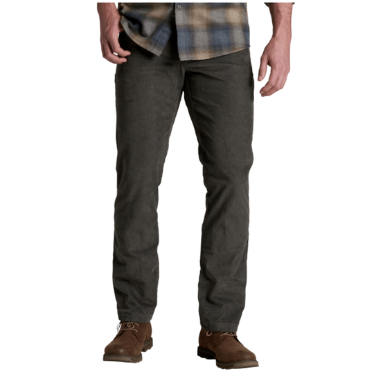 A person wearing dark charcoal gray straight-leg work pants, a brown and blue plaid shirt, and brown leather work boots, shown from the waist down on a white background.