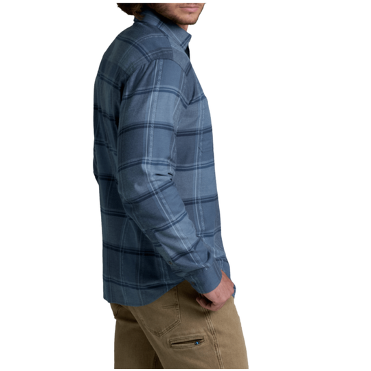 A man wearing a blue and gray plaid long-sleeve button-up shirt, shown from a side profile against a plain white background.