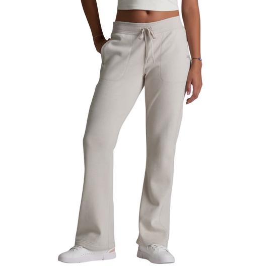 A person wearing light beige drawstring scrub pants with a white crop top and white sneakers, shown from the waist down on a plain white background.