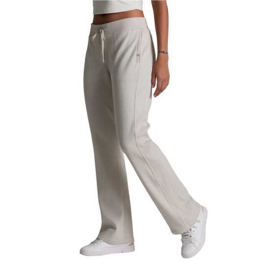 A side view of a person wearing light beige wide-leg sweatpants with a drawstring waist, paired with white sneakers against a plain white background.