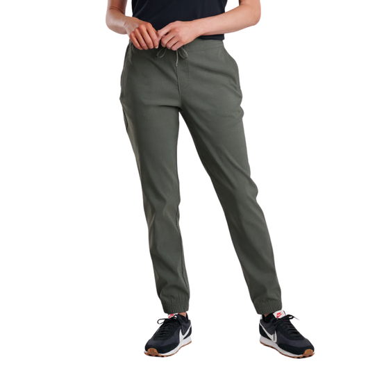 A person wearing olive green jogger-style pants with elastic cuffs, shown from the waist down against a plain white background. The model is also wearing a dark top and black athletic sneakers.