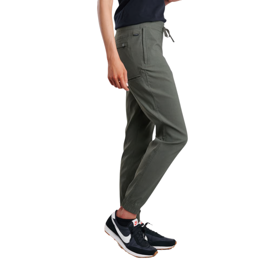 A person wearing olive green jogger-style pants with a drawstring waist and side cargo pocket, paired with dark sneakers, shown against a plain white background.
