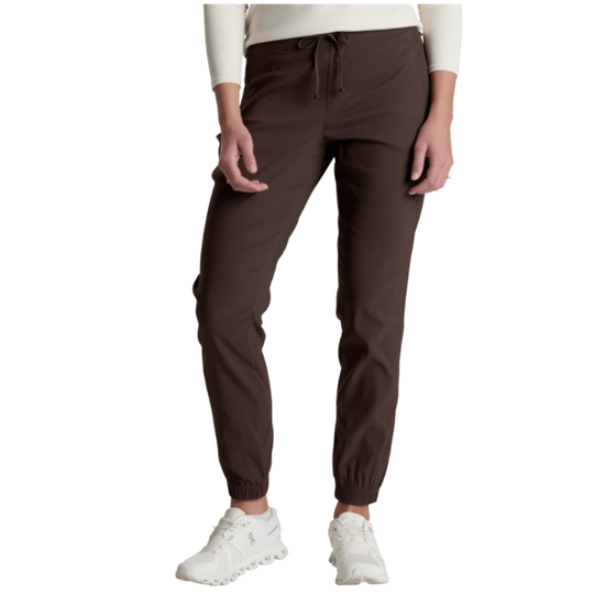 A person wearing dark brown jogger-style pants with a drawstring waist and elastic cuffs, paired with a cream top and white sneakers, shown against a plain white background.