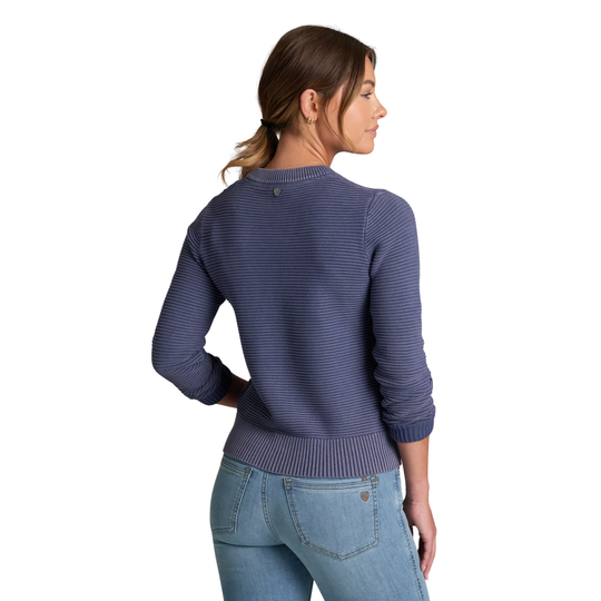 A woman shown from the back wearing a navy blue ribbed knit sweater and light blue jeans against a plain white background.