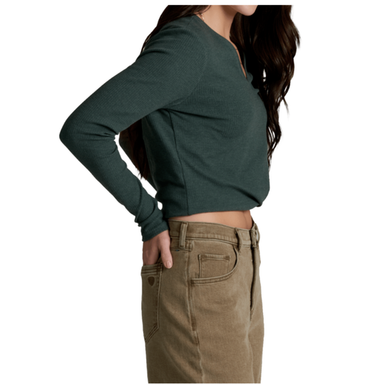 A woman wearing a dark green long-sleeve cropped V-neck top and tan high-waisted jeans, shown from the side against a plain white background.
