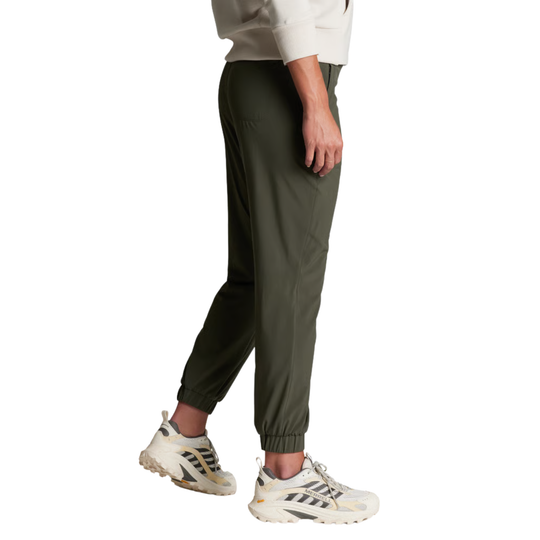 A person wearing olive green jogger-style pants with elastic cuffs, paired with white and beige athletic sneakers, shown from the waist down on a plain white background.