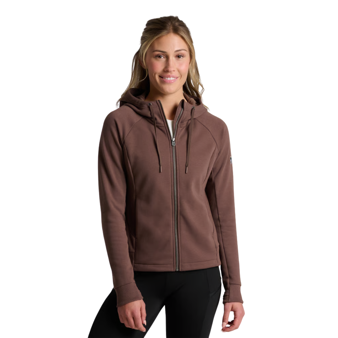 A woman wearing a brown full-zip hooded sweatshirt and black pants, standing against a plain white background.