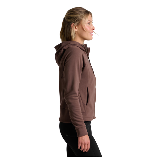 A woman shown in side profile wearing a brown zip-up hoodie and black pants against a plain white background.