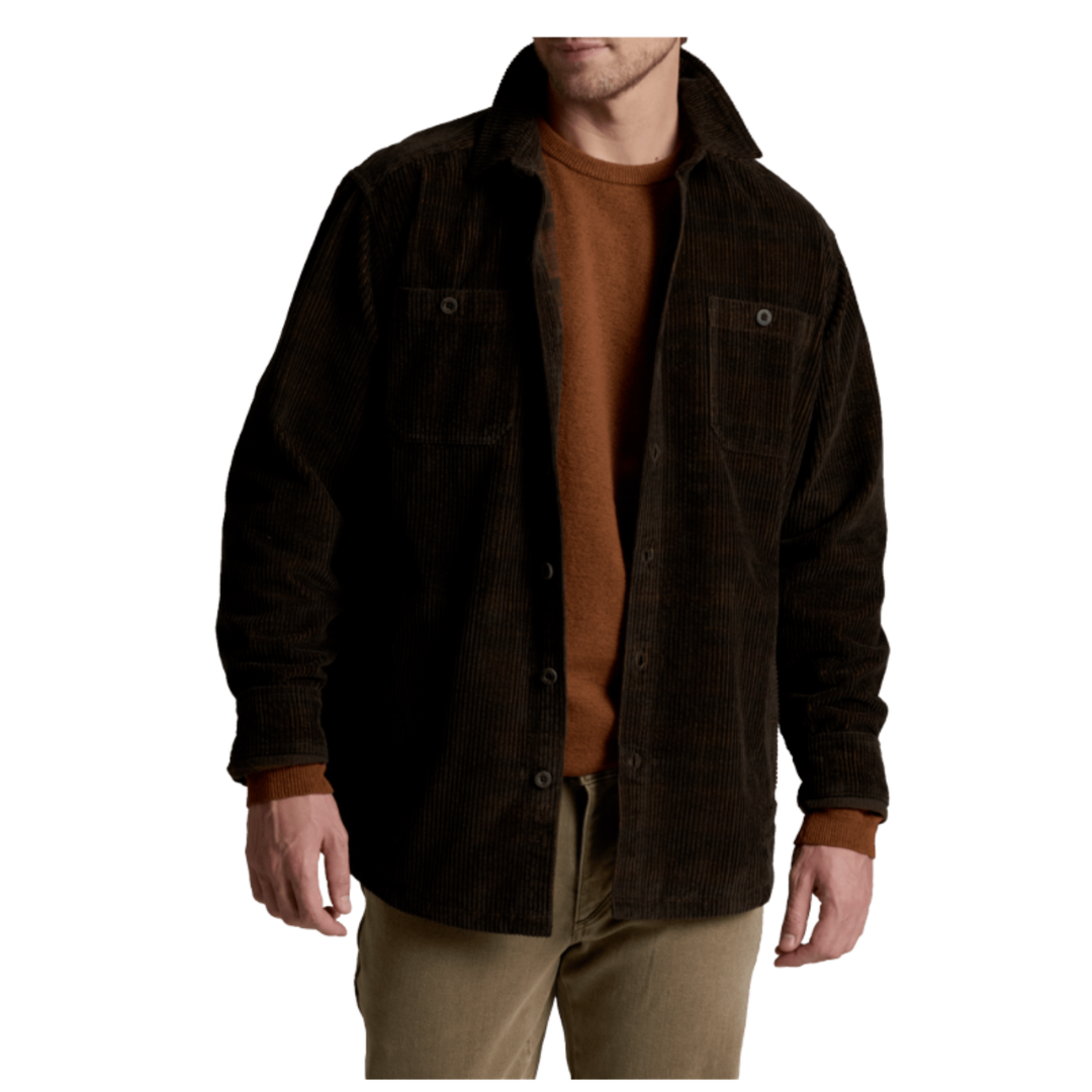A man wearing a dark brown corduroy button-up shirt jacket over a rust-brown t-shirt and khaki pants, shown from the chest down against a plain white background.