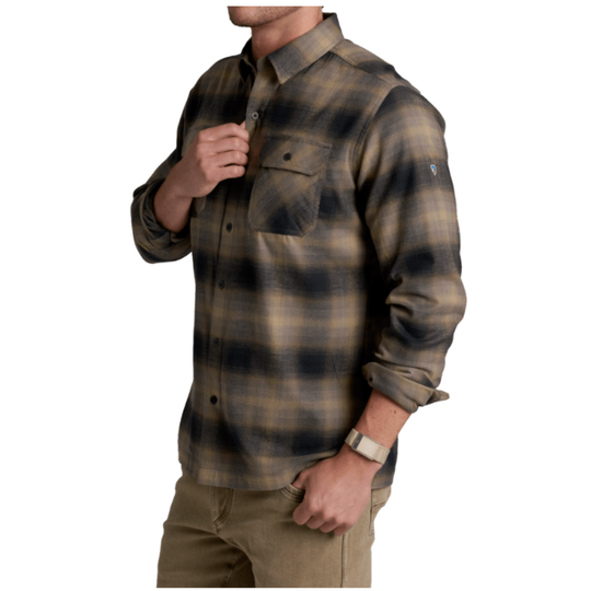 A man wearing a long-sleeve plaid button-up shirt in brown and black tones, paired with khaki pants, shown against a plain white background.