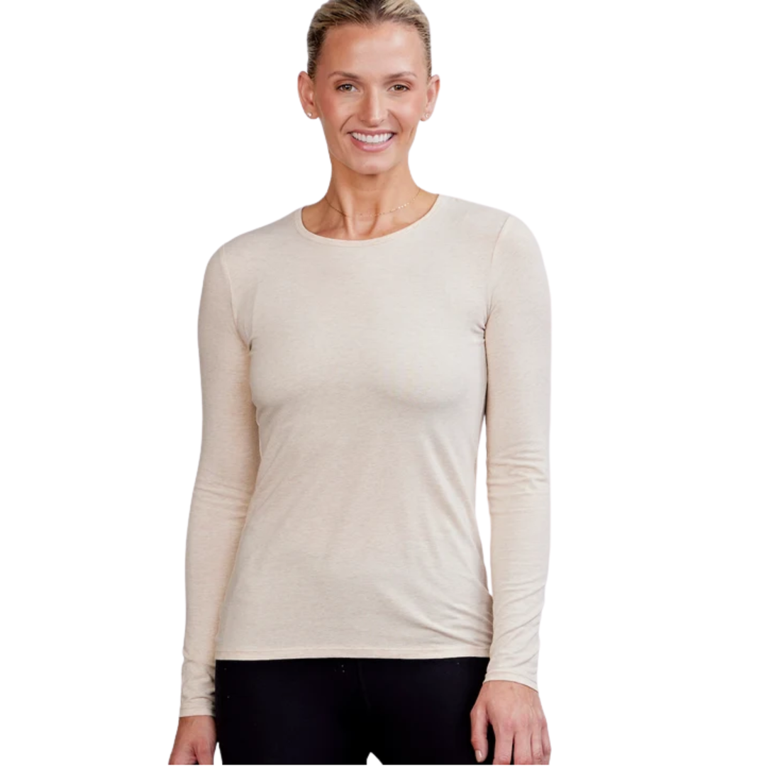 A woman modeling a light beige long-sleeve crewneck shirt against a plain white background.