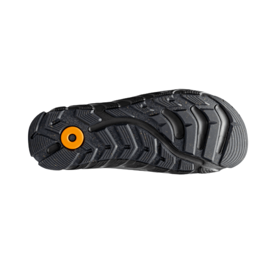 A close-up of a black textured rubber sole with a distinctive chevron tread pattern and a bright orange circular accent near the heel, shown against a plain white background.