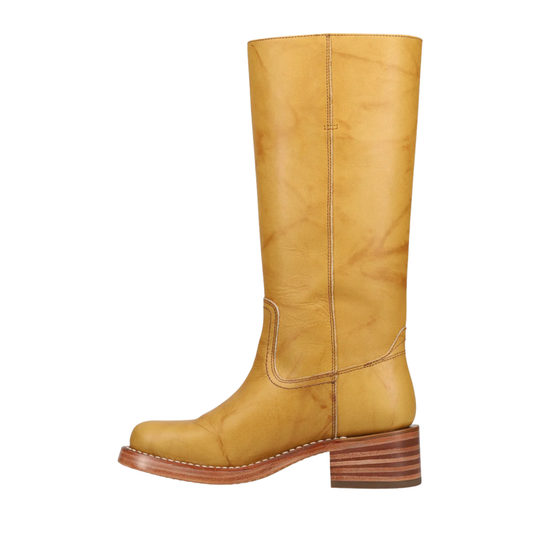 A single mid-calf leather boot in a warm mustard yellow color, featuring a stacked brown wooden heel and a low block sole, shown against a plain white background.