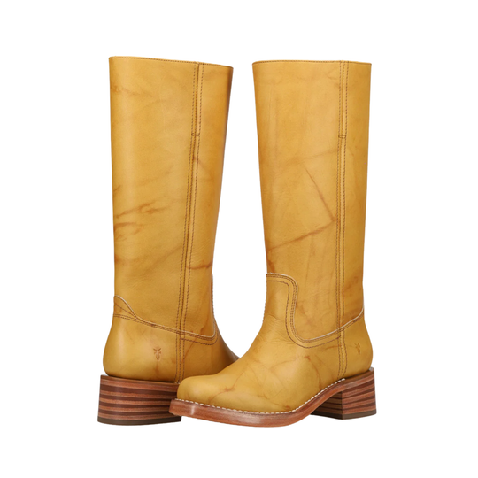 A pair of tall, knee-high western boots in a mustard yellow leather, featuring stacked brown wooden heels and contrast stitching, shown against a plain white background.