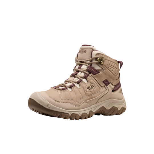 A mid-cut Keen hiking boot in beige with dark brown and burgundy accents, shown from a side profile on a white background.