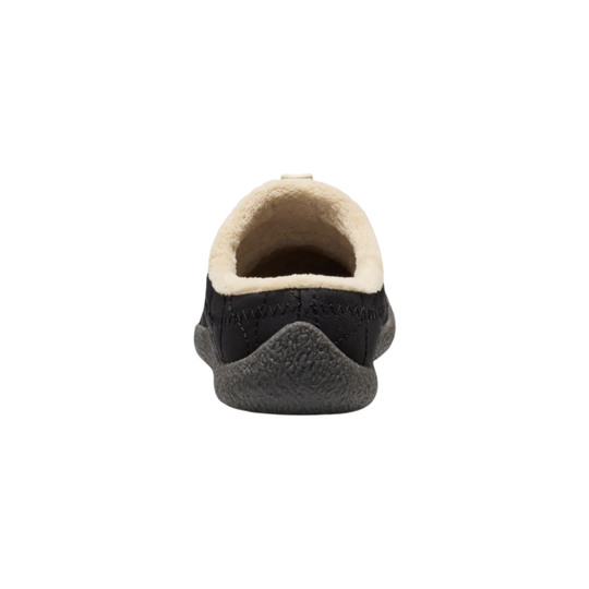A single black slip-on mule shoe with a quilted upper, a light beige fleece lining, and a dark gray textured sole, shown against a plain white background.