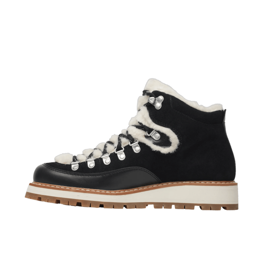 A high-top winter boot in black suede and leather with white faux-fur trim, white laces, and a thick white midsole with a brown gum outsole, shown from a side profile on a white background.