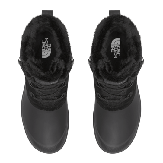 A pair of black winter boots with plush faux-fur trim around the collar, shown from a top-down view on a white background. The brand 'The North Face' is visible on the inner sole of each boot.