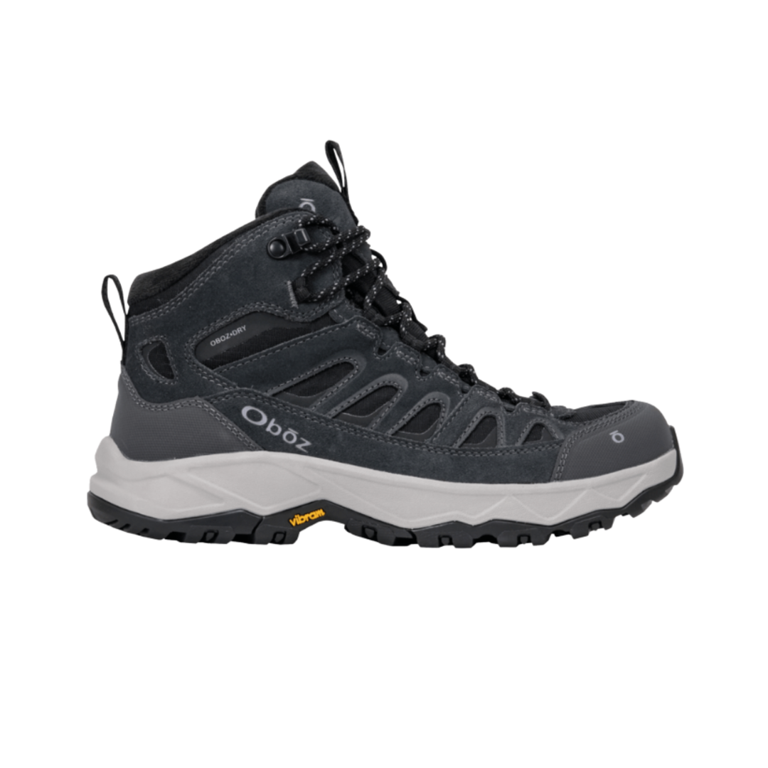 A dark gray and black Oboz mid-top hiking boot with a white midsole and Vibram outsole, shown from a side profile on a white background.
