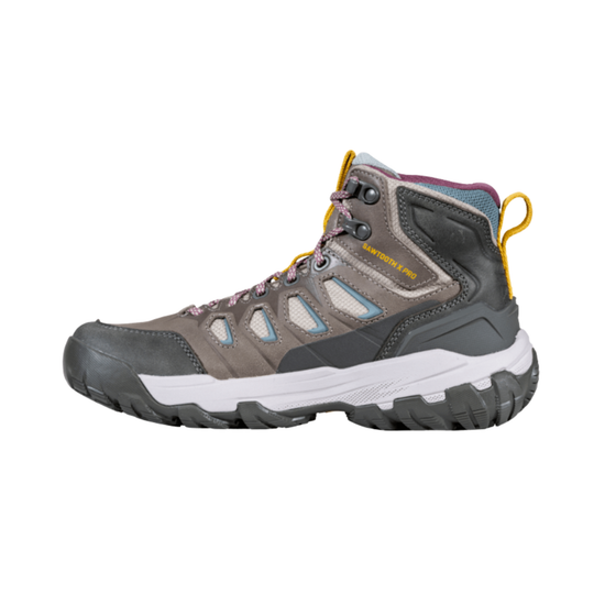 A mid-top hiking boot in gray and black with white midsole, yellow pull tabs, and light blue accents, shown from a side profile on a white background.