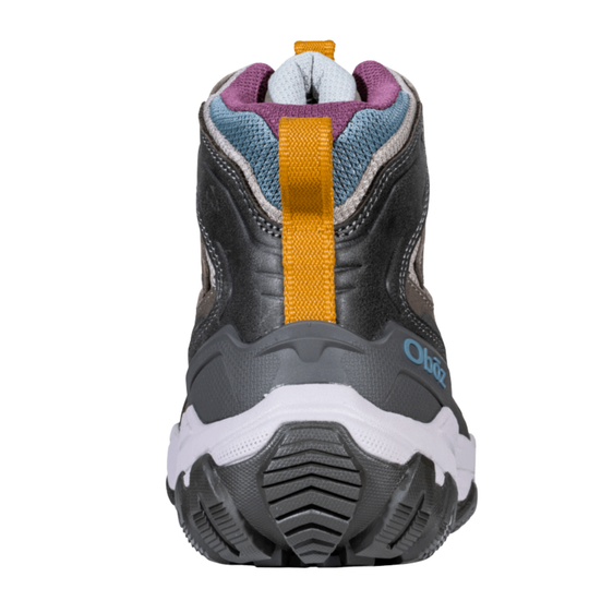 A rear view of a children's mid-height hiking boot, featuring a dark gray and black upper with a prominent mustard yellow vertical strap, a white midsole, and purple lining details.