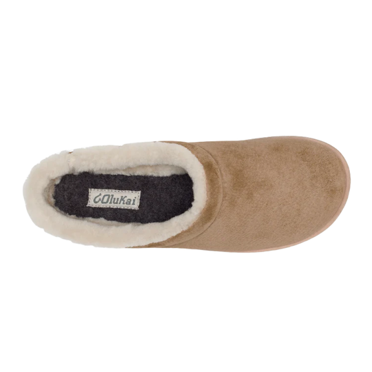 A top-down view of a tan suede slipper with a white shearling lining and a dark gray interior, featuring a visible 'Olukai' brand label.