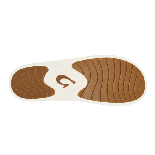 A close-up of a shoe sole showing a brown textured tread pattern on a white base, with the brand name 'Olukai' faintly visible on the heel area.