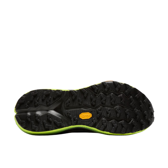 The black rubber outsole of a trail running shoe, featuring deep lugs and a small orange Vibram logo, with a bright neon green accent line along the edge.