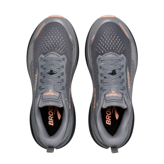 A pair of Brooks Cascadia running shoes shown from a top-down view, featuring a dark gray and black mesh upper with peach accents and the brand name 'BROOKS' printed on the tongue and insole.