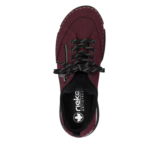 A top-down view of a rieker shoe in burgundy and black, featuring black laces and a black heel counter with the Reiki logo.