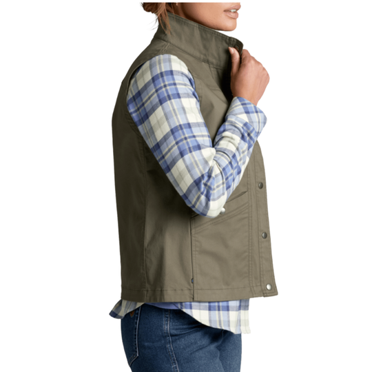 A woman wearing an olive green sleeveless button-front vest over a blue and white plaid flannel shirt, paired with blue jeans, shown from the side against a plain white background.