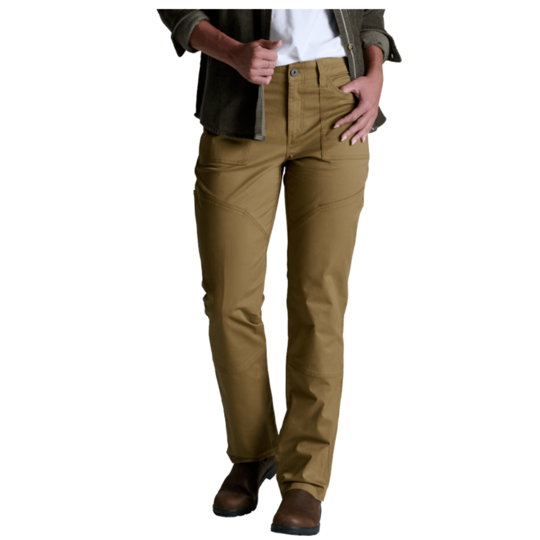 A person wearing tan straight-leg pants with a white shirt, dark olive jacket, and brown boots, shown from the waist down on a plain white background.