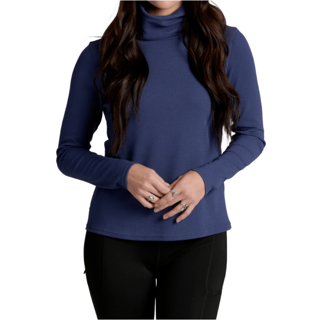 A woman wearing a long-sleeve ribbed turtleneck top in navy blue, paired with black leggings, shown against a plain white background.