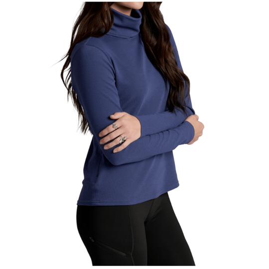 A woman wearing a long-sleeve, high-neck turtleneck top in a muted blue color, paired with black leggings, shown against a plain white background.