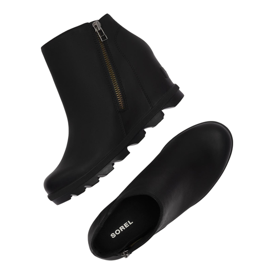 A pair of black Sorel ankle boots shown from two angles: a side profile displaying a gold zipper on the outer side, and a top-down view showing the black interior with the Sorel brand name printed in white.