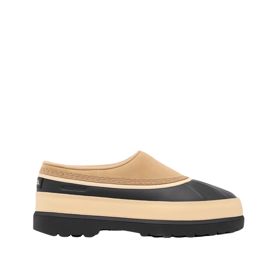 A slip-on shoe with a beige suede upper, a black rubber toe cap, a beige midsole stripe, and a black lug sole, shown from a side profile on a white background.