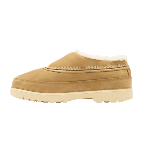 A tan suede slip-on slipper with a cream-colored faux-fur lining and a thick cream sole, shown in a side profile on a white background.