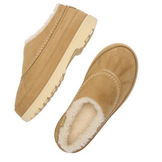 A pair of tan suede slip-on slippers with a cream shearling lining, shown from top and side angles on a white background.