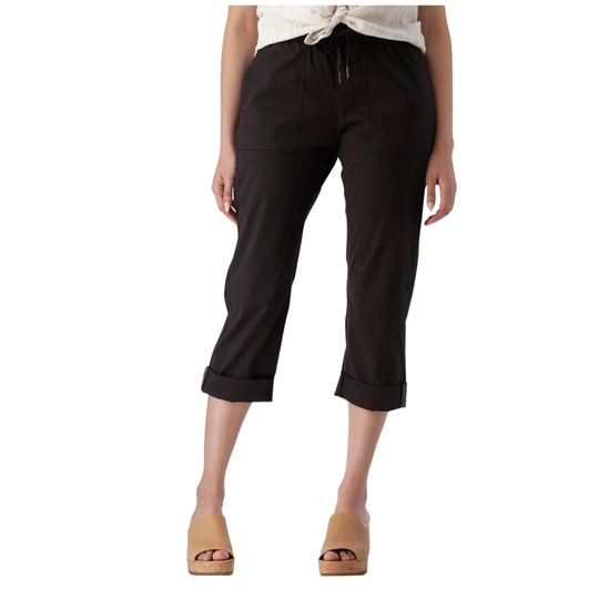 A model wearing black cropped pants with a drawstring waist and rolled cuffs, paired with tan wedge sandals and a cream top, shown against a plain white background.