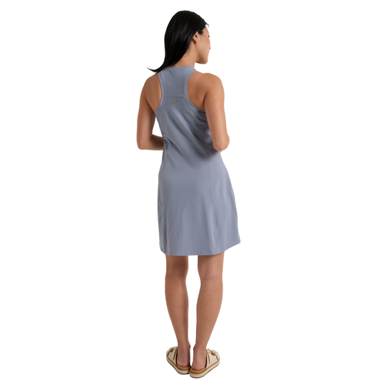 A woman wearing a sleeveless, knee-length athletic dress in a dusty periwinkle blue color, shown from a back profile against a plain white background.
